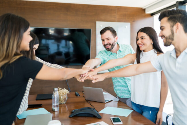 Business Team With Hands Stacked Together In Meeting